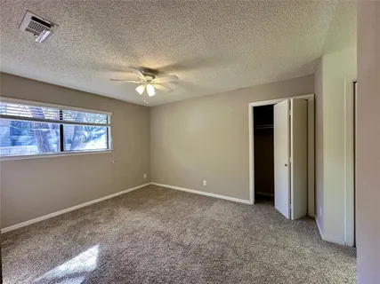 an empty room with a chandelier fan and windows