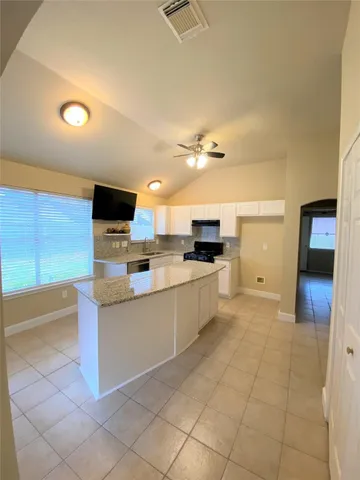 a large white kitchen with a sink and dishwasher a stove top oven with wooden floor