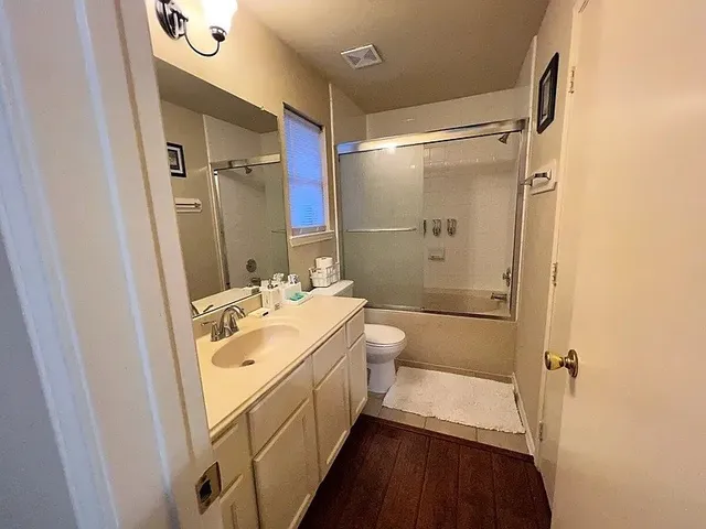 a bathroom with a sink a toilet a mirror and shower