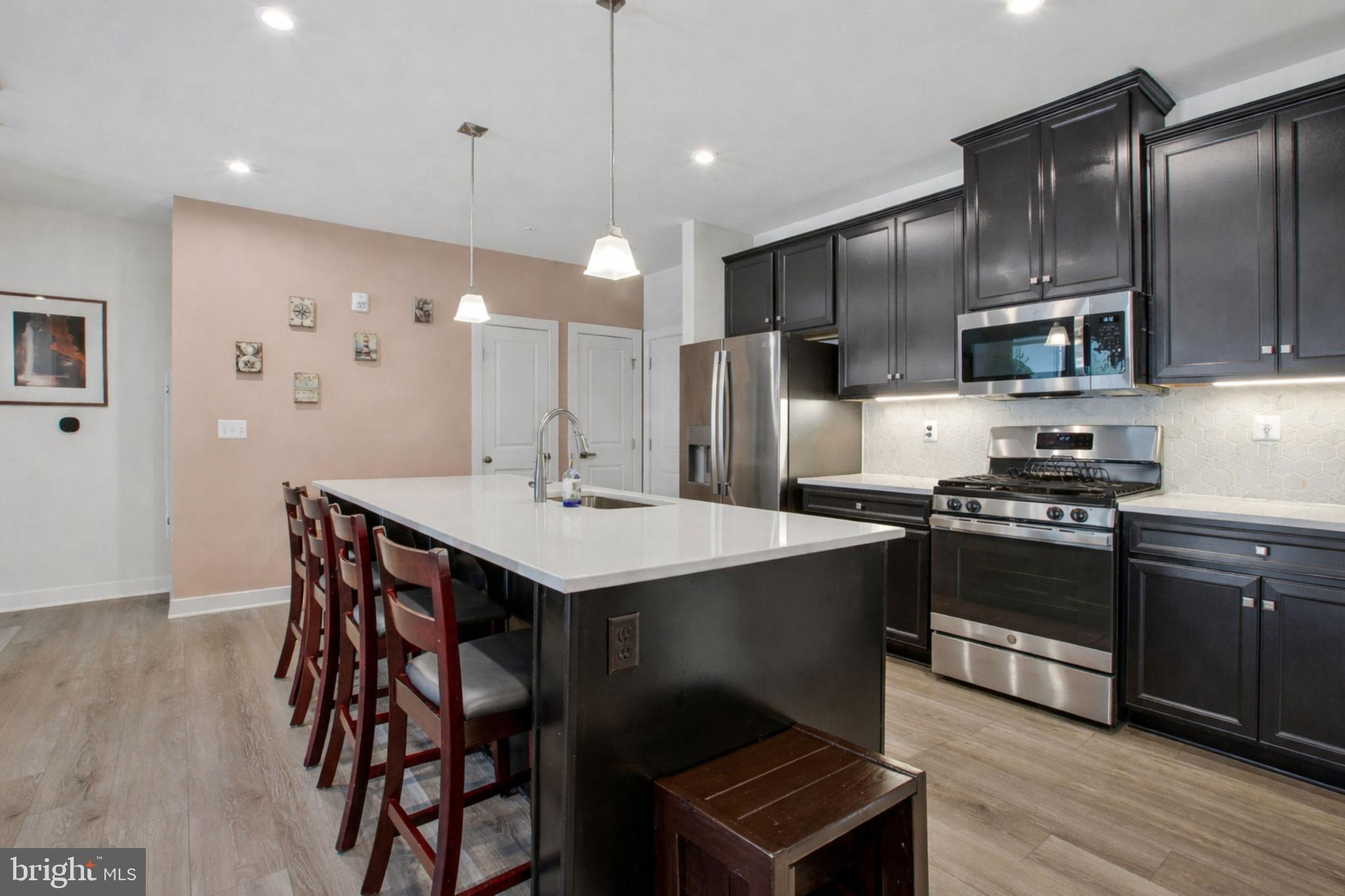 10401 Resort Road, Unit F Ellicott City, MD 21042 - Photo 2 of 13 a kitchen with stainless steel appliances kitchen island granite countertop a sink a stove a refrigerator and island with wooden floor