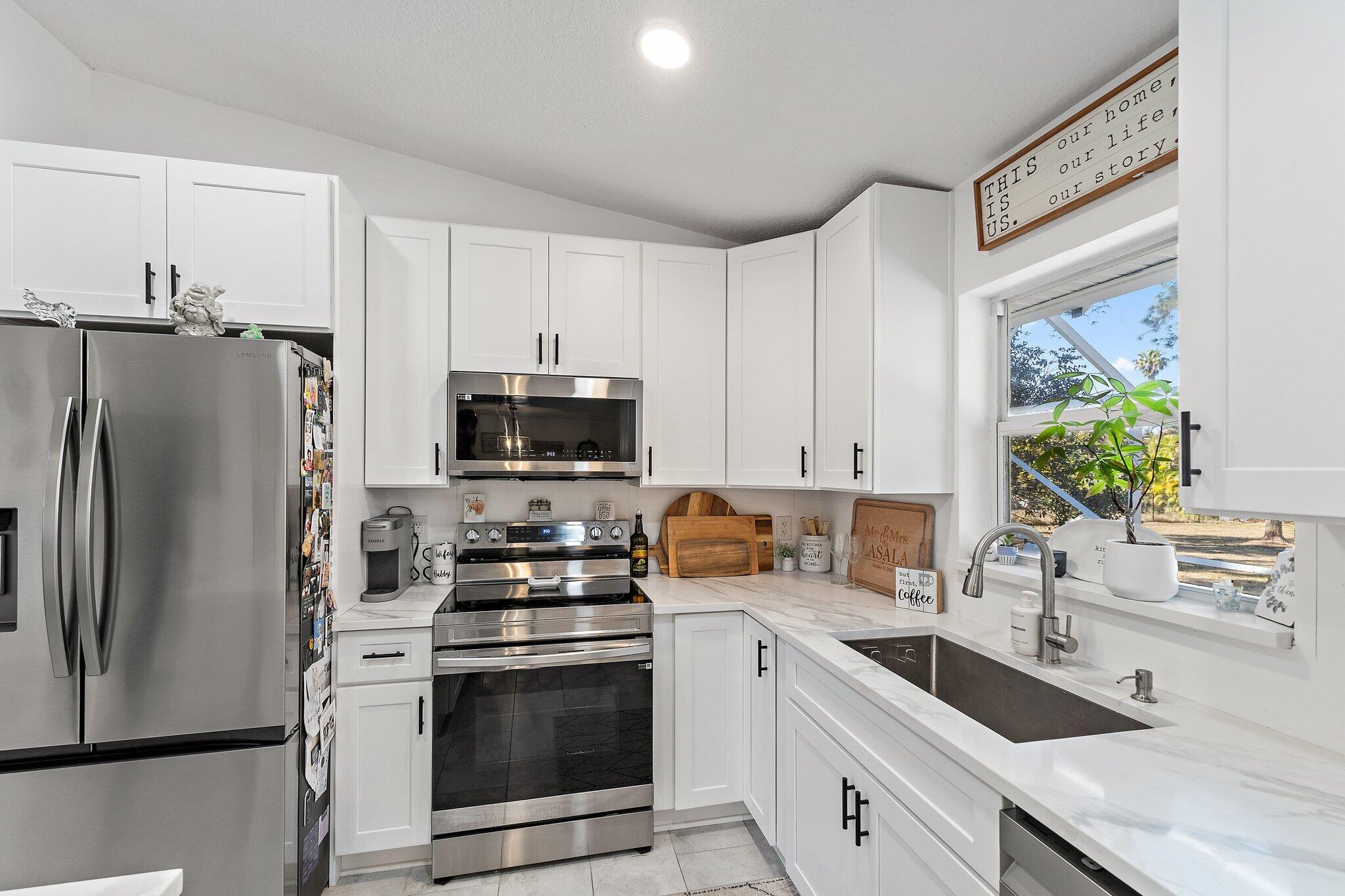 18389 41st Road North Loxahatchee, FL 33470 - Photo 10 of 33 a kitchen with stainless steel appliances white cabinets a sink a stove a refrigerator and a microwave