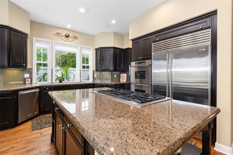 a kitchen with kitchen island granite countertop a sink appliances and cabinets