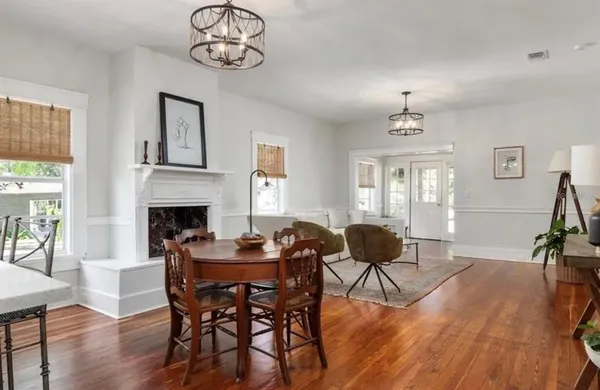 a dining room with wooden floor a chandelier a wooden table and chairs