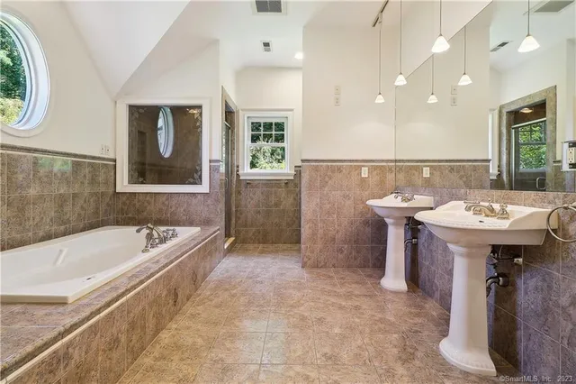 a bathroom with a tub a sink and mirror