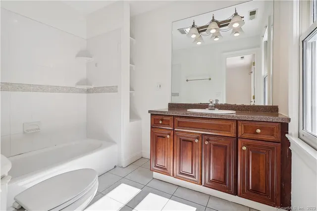 a bathroom with a granite countertop bathtub sink vanity and mirror