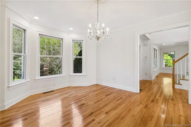 a view of a room with wooden floor chandelier and windows