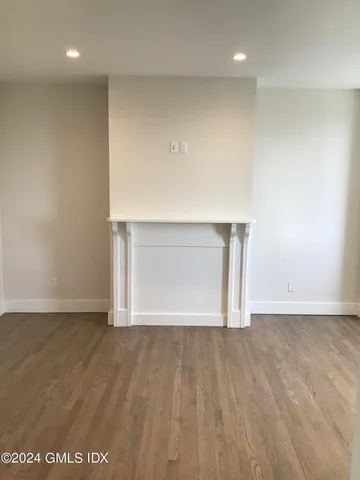 a view of an empty room with wooden floor and a cabinet