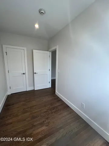 a view of an empty room with wooden floor and closet