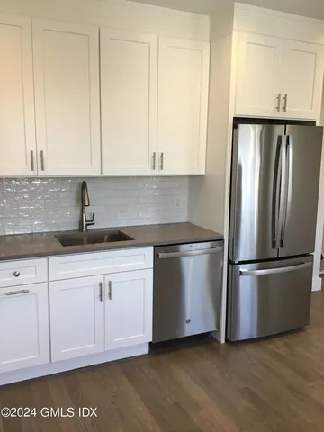 a kitchen with stainless steel appliances granite countertop a refrigerator sink and white cabinets