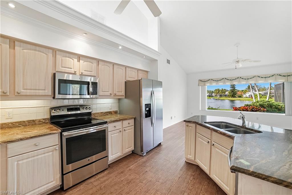 10969 Phoenix Way Naples, FL 34119 - Photo 5 of 20 a kitchen with stainless steel appliances white cabinets a stove a sink and a microwave
