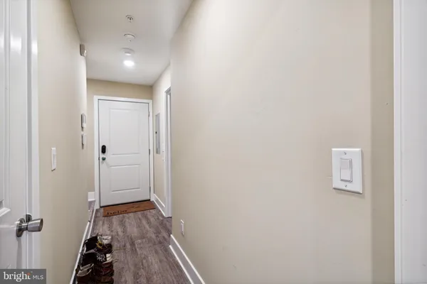 a view of a hallway with wooden floor and a bathroom