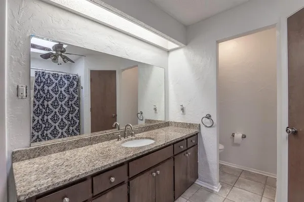 a bathroom with a granite countertop sink a mirror and shower