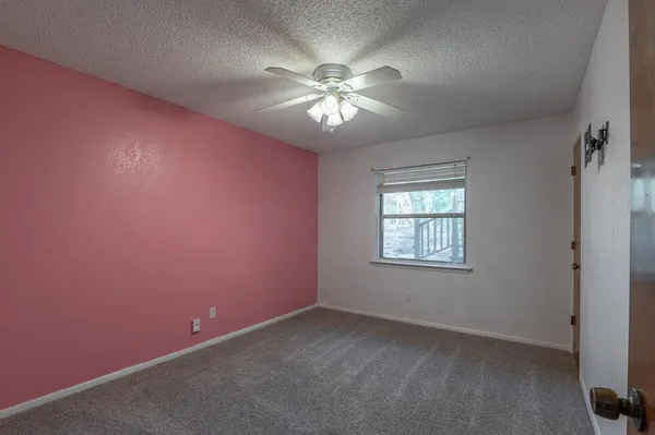 an empty room with a window and a fan