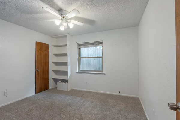 an empty room with windows and fan