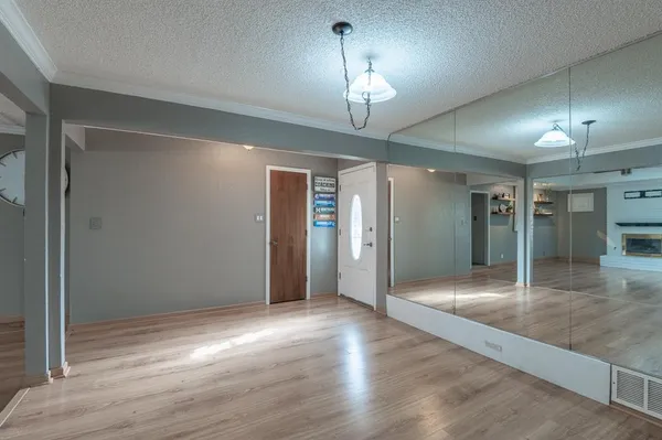 an empty room with wooden floor and chandelier