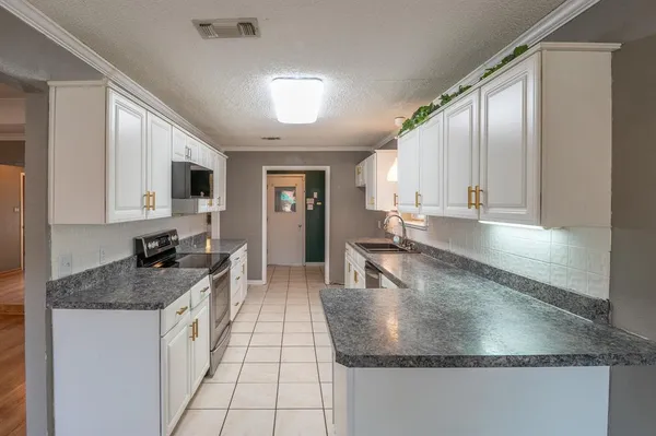 a kitchen with granite countertop a sink a stove and cabinets