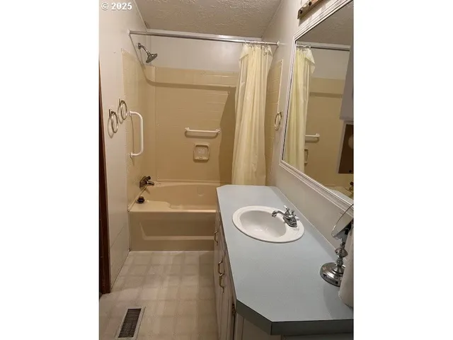 a bathroom with a granite countertop sink a mirror a bathtub and shower