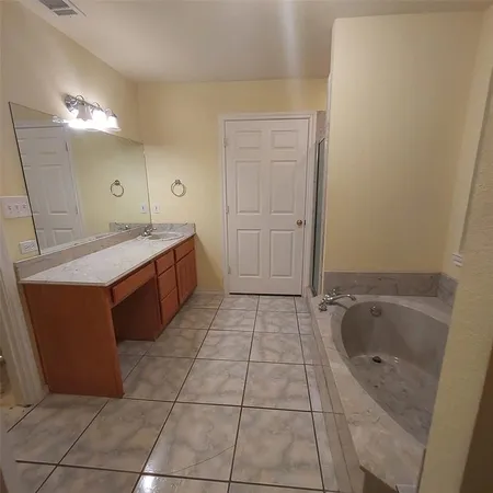 a spacious bathroom with a granite countertop sink a mirror and bathtub