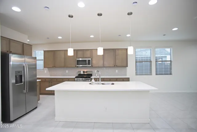 a large kitchen with stainless steel appliances kitchen island a sink dishwasher a stove and a refrigerator with wooden floor