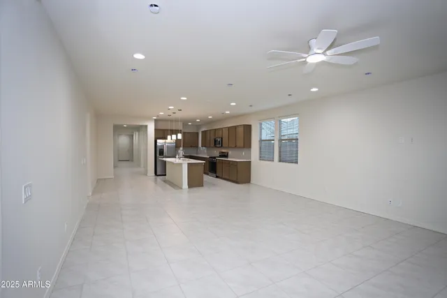 an empty room with chandelier fan and windows