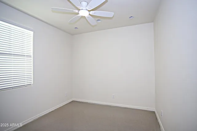 an empty room with a window and a fan