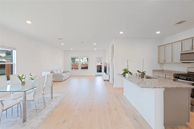 a large white kitchen with a stove a sink a couch and a dining table