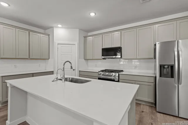 a kitchen with stainless steel appliances a refrigerator a sink a stove a microwave and cabinets