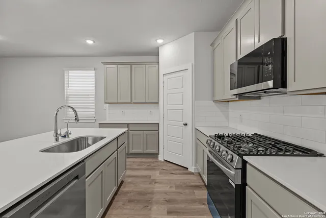 a kitchen with stainless steel appliances a sink stove top oven and cabinets