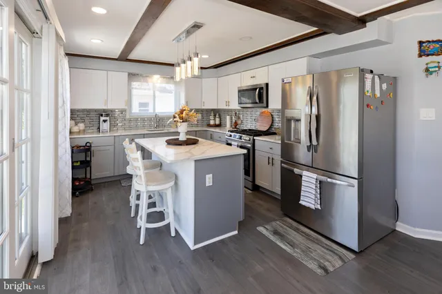 a kitchen with stainless steel appliances a refrigerator a stove a sink and white cabinets with wooden floor