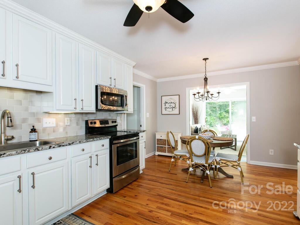 15 Devonshire Drive Candler, NC 28715 - Photo 11 of 43 a kitchen with stainless steel appliances granite countertop a stove top oven a sink a dining table and chairs with wooden floor