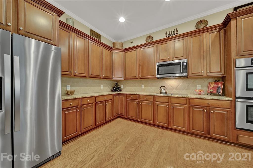 392 Windell Drive Fort Mill, SC 29708 - Photo 11 of 40 a kitchen with kitchen island granite countertop wooden cabinets a refrigerator and a sink