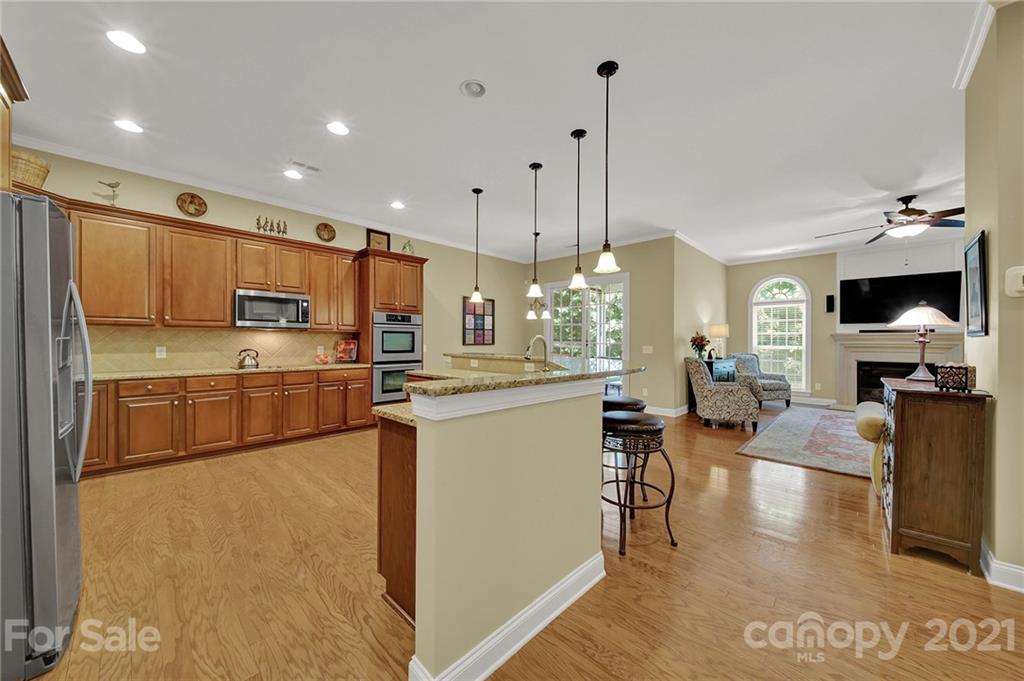 392 Windell Drive Fort Mill, SC 29708 - Photo 9 of 40 a kitchen with stainless steel appliances kitchen island granite countertop a refrigerator a stove top oven a sink dishwasher and white cabinets with wooden floor