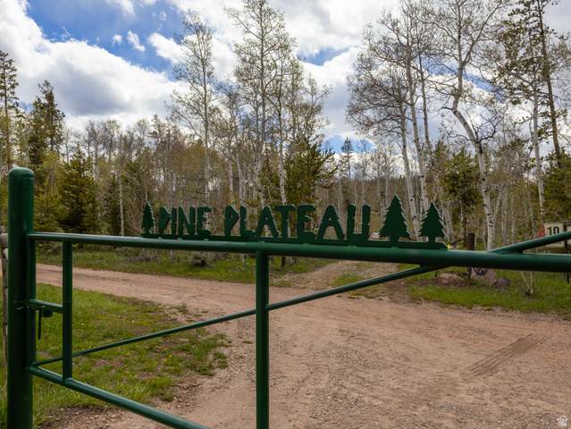 5082 Pine Crest Road Evanston, UT 82930 - Photo 2 of 25 Green metal gate with "PINE PLATEAU" lettering and pine tree accents