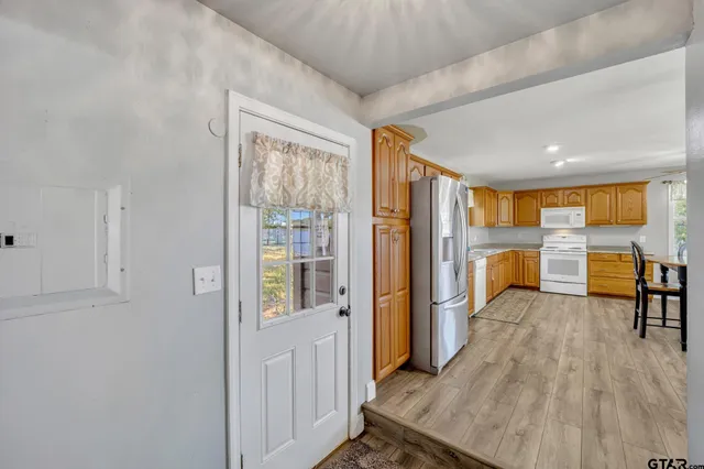 a view of a kitchen with refrigerator and wooden floor