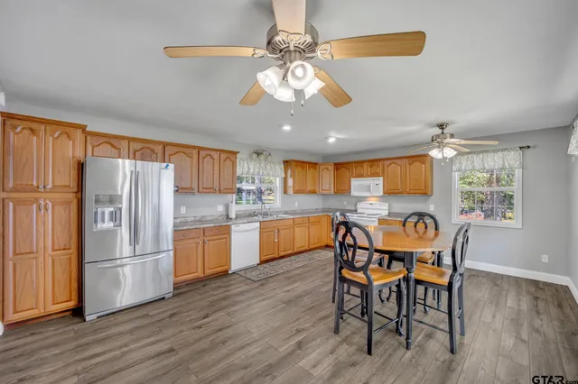 a kitchen with stainless steel appliances granite countertop a dining table chairs refrigerator and sink