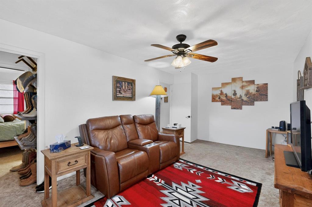 202 Senter Valley Road Irving, TX 75060 - Photo 16 of 32 Carpeted living area featuring a ceiling fan with light fixture, white walls, and a doorway opening to an adjacent room