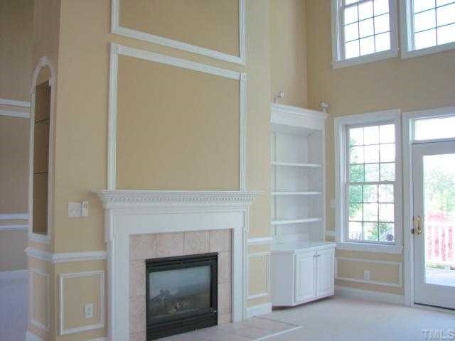 9012 Winged Thistle Court Raleigh, NC 27617 - Photo 7 of 12 The 2 story living room and the 2-story family room share the warmth and beauty of a gas fireplace. There are built-in cabinets in the family room. Both rooms have views of the golf course.