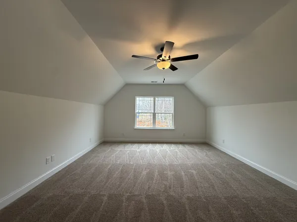 an empty room with chandelier fan and windows
