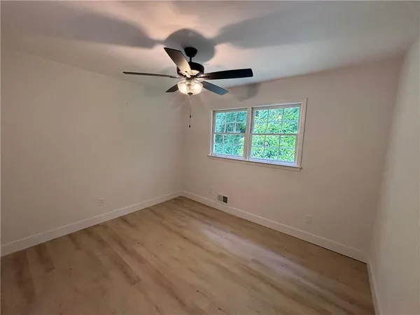 an empty room with a window and a fan