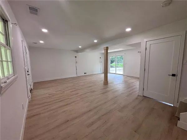 an empty room with wooden floor and windows