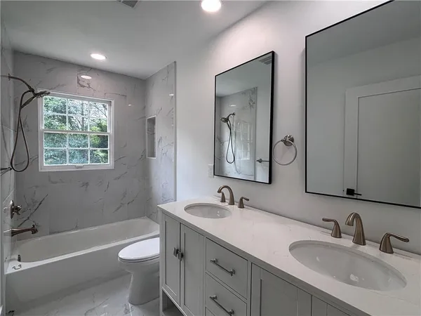 a bathroom with a double vanity sink toilet a large mirror a bathtub and shower