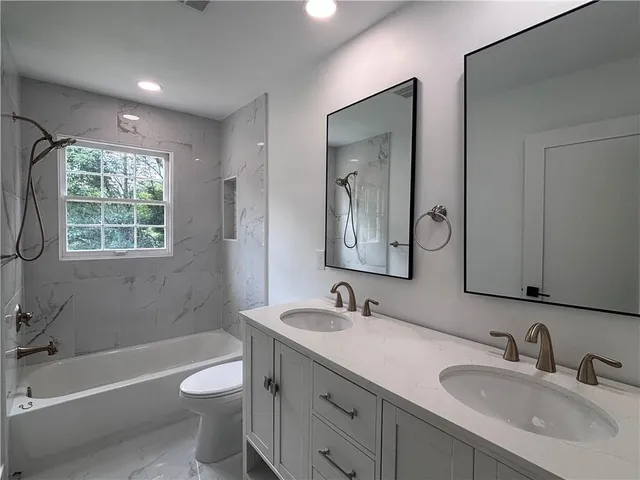 a bathroom with a double vanity sink toilet a large mirror a bathtub and shower