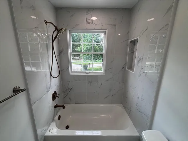 a bathroom with a tub a window and a shower