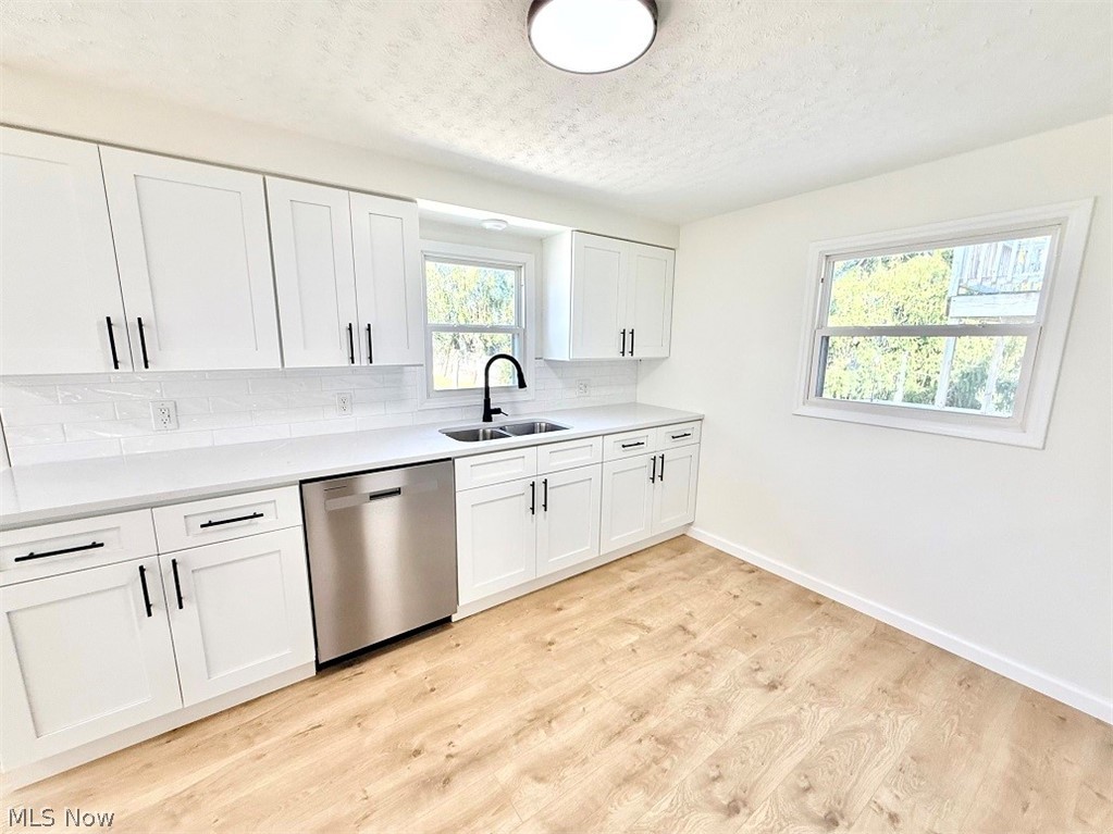 144 Aberdeen Road Steubenville, OH 43953 - Photo 14 of 34 Kitchen with stainless steel dishwasher, white cabinets, light wood-type flooring, decorative backsplash, and a textured ceiling