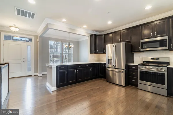 a kitchen with stainless steel appliances granite countertop a refrigerator a stove a sink and dishwasher with wooden floor