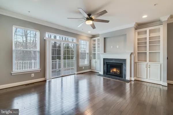 a view of an empty room with wooden floor and a fireplace