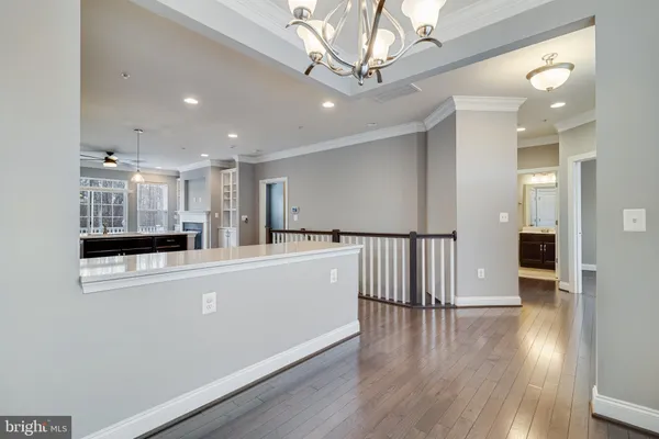a view of a hallway with wooden floor and chandelier