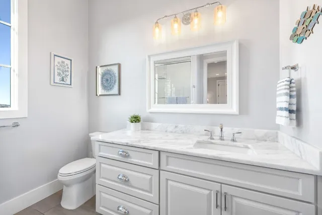 a bathroom with a granite countertop toilet sink and mirror