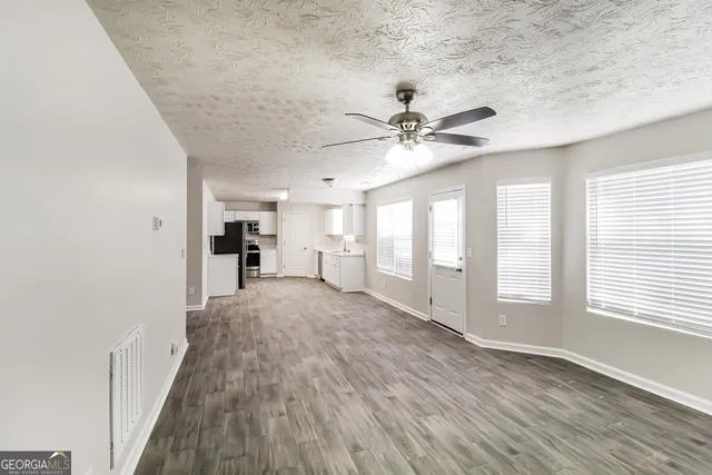 a kitchen with granite countertop a refrigerator stove and sink with wooden floor