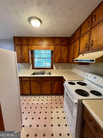 a kitchen with granite countertop a sink a stove a microwave a cabinets and a counter top space